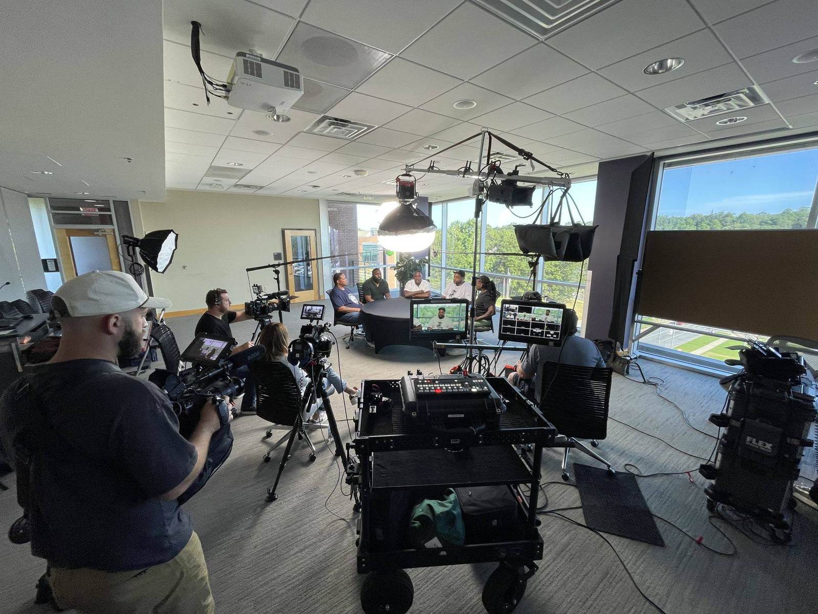 A professional video production crew filming a multi-person interview on location in Arkansas with lighting and cameras