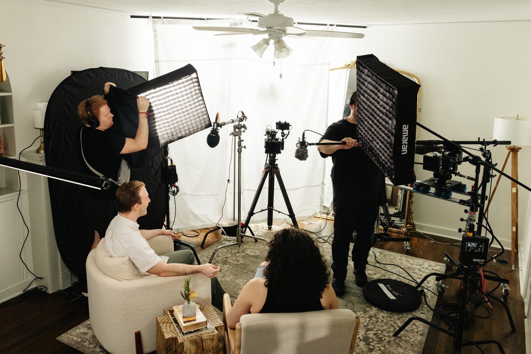 Three-person video production crew filming a corporate interview in Arkansas with cinema camera, Amaran softbox lighting, boom microphone, and dolly track